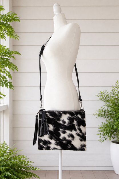 Handcrafted genuine cowhide crossbody purse with hair-on-hide front, leather tassel, adjustable strap, and western leather design for everyday wear, travel, rodeos, and concerts.