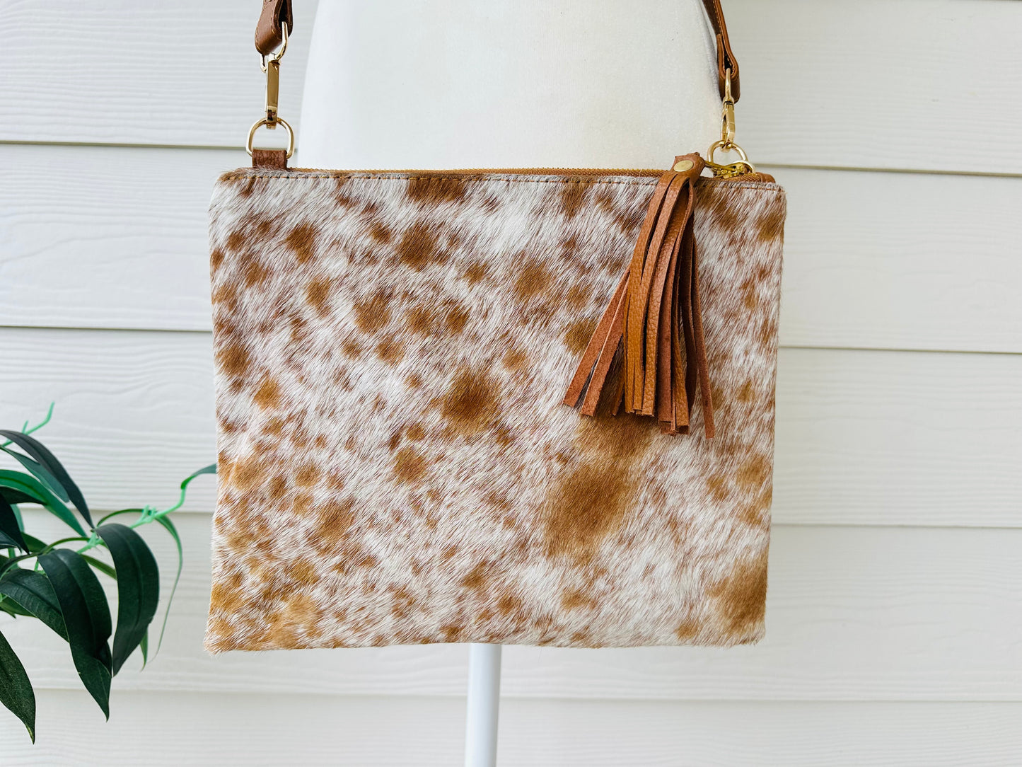 Handcrafted genuine cowhide crossbody purse with hair-on-hide front, leather tassel, adjustable strap, and western leather design for everyday wear, travel, rodeos, and concerts.