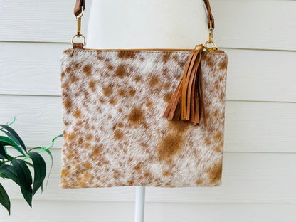 Handcrafted genuine cowhide crossbody purse with hair-on-hide front, leather tassel, adjustable strap, and western leather design for everyday wear, travel, rodeos, and concerts.