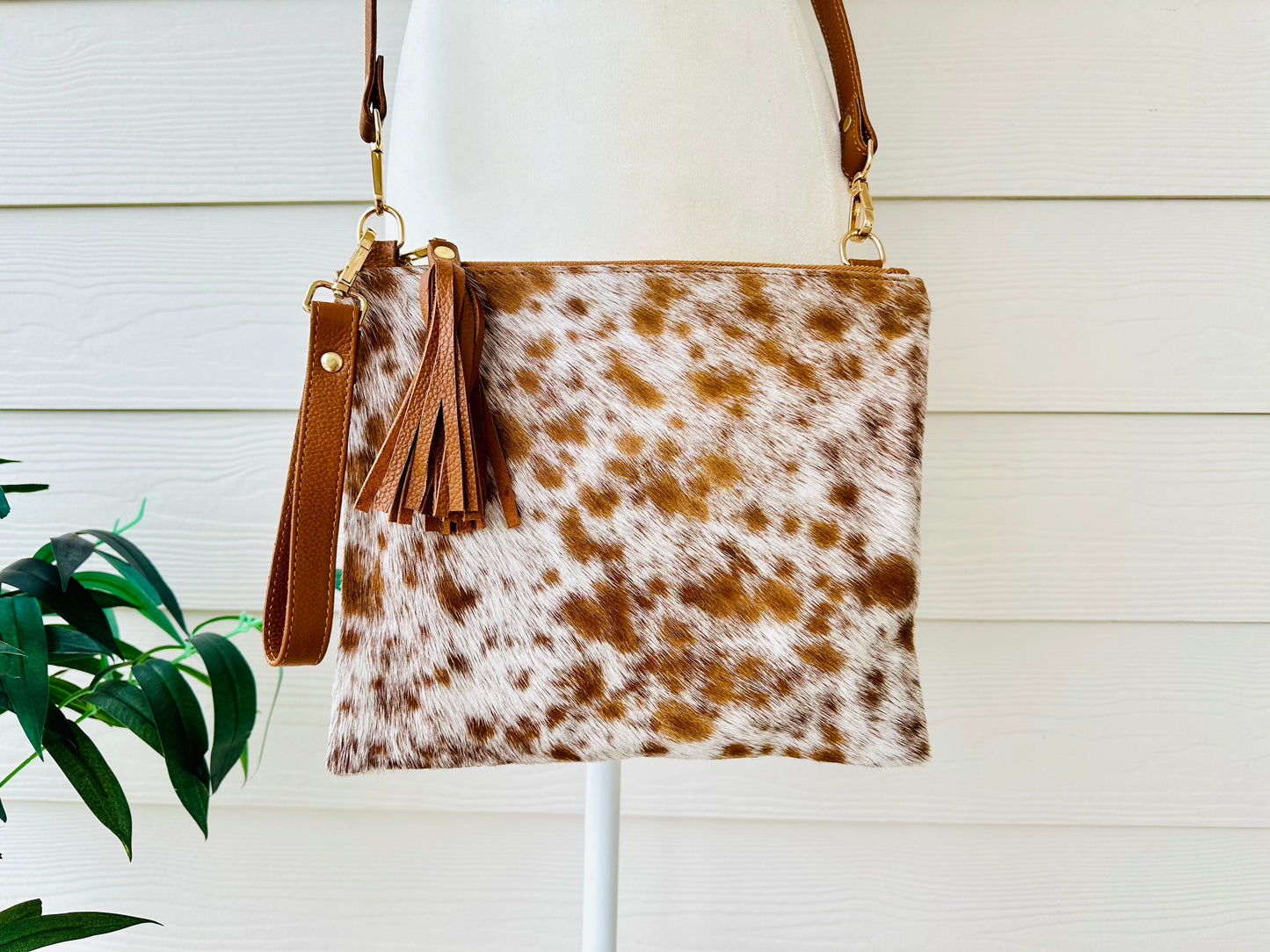 Handcrafted genuine cowhide crossbody purse with hair-on-hide front, leather tassel, adjustable strap, and western leather design for everyday wear, travel, rodeos, and concerts.