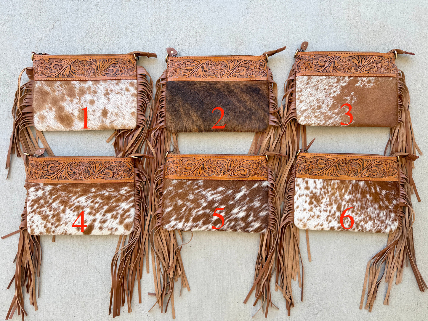 Handcrafted genuine cowhide crossbody bag with floral tooled leather, long leather fringe, adjustable strap, and zip-top closure for western, rodeo, and everyday style.
