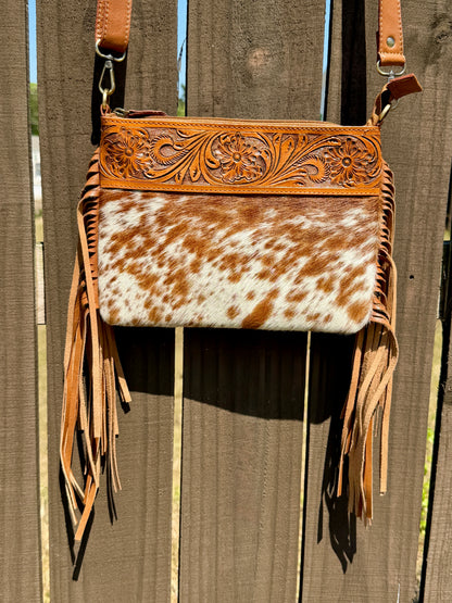 Handcrafted genuine cowhide crossbody bag with floral tooled leather, long leather fringe, adjustable strap, and zip-top closure for western, rodeo, and everyday style.