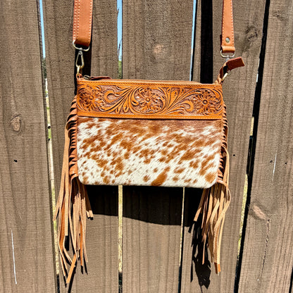 Handcrafted genuine cowhide crossbody bag with floral tooled leather, long leather fringe, adjustable strap, and zip-top closure for western, rodeo, and everyday style.