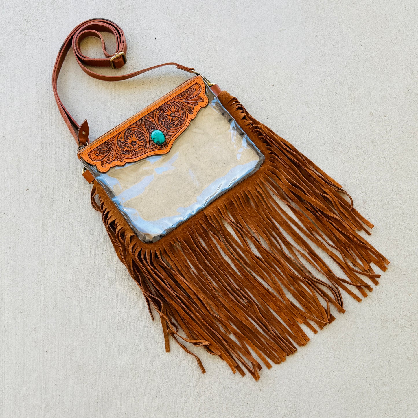 Stadium-approved clear western crossbody bag with genuine leather fringe, turquoise stone accent, adjustable strap, and zip closure for concerts, rodeos, and festivals.