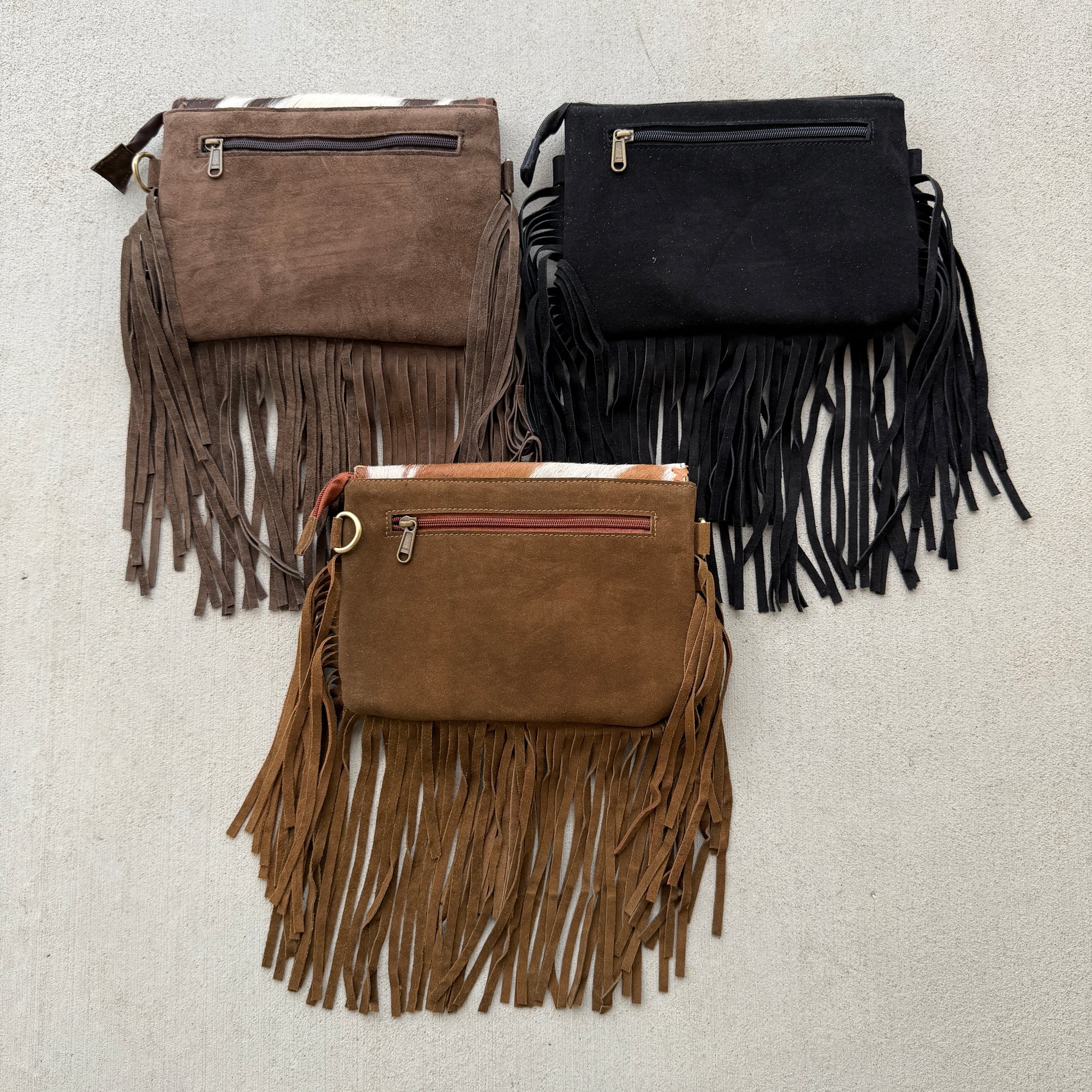 Handcrafted genuine cowhide fringe crossbody purse with whipstitched flap, leather tassel, adjustable strap, and western hair-on-hide design for rodeos, concerts, and everyday wear.