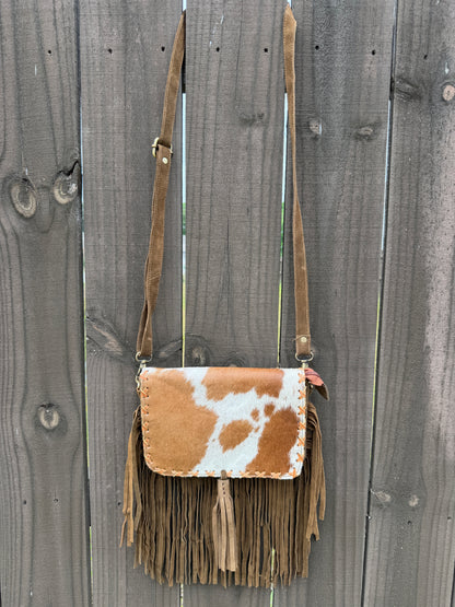Handcrafted genuine cowhide fringe crossbody purse with whipstitched flap, leather tassel, adjustable strap, and western hair-on-hide design for rodeos, concerts, and everyday wear.