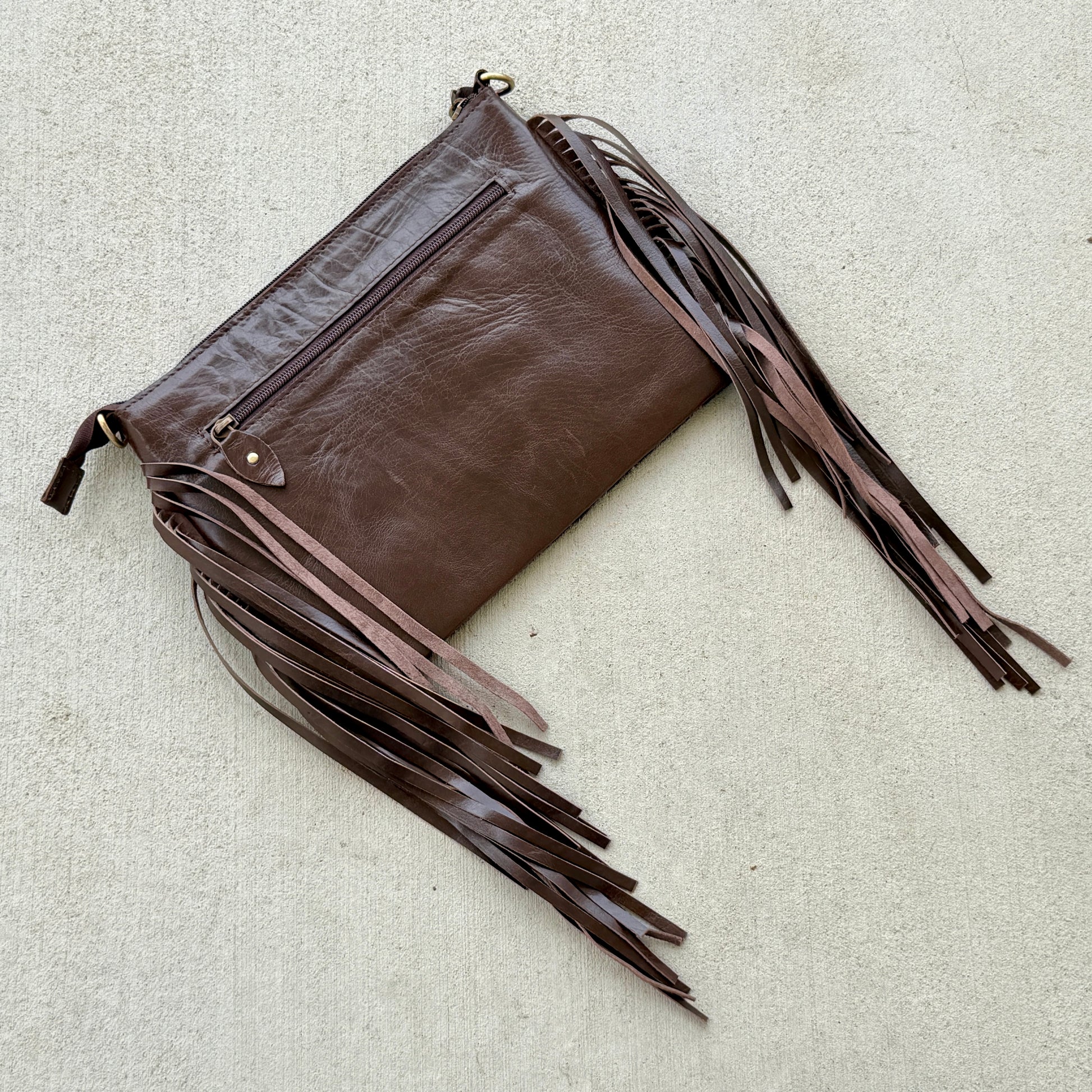 Handcrafted genuine cowhide crossbody bag with floral tooled leather, long leather fringe, adjustable strap, and zip-top closure for western, rodeo, and everyday style.
