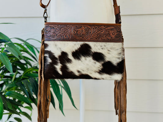 Handcrafted genuine cowhide crossbody bag with floral tooled leather, long leather fringe, adjustable strap, and zip-top closure for western, rodeo, and everyday style.