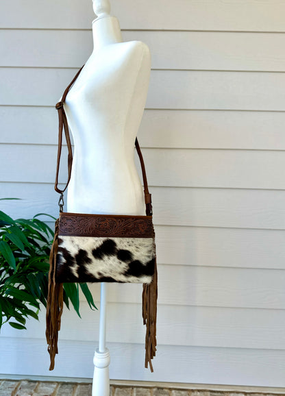 Handcrafted genuine cowhide crossbody bag with floral tooled leather, long leather fringe, adjustable strap, and zip-top closure for western, rodeo, and everyday style.