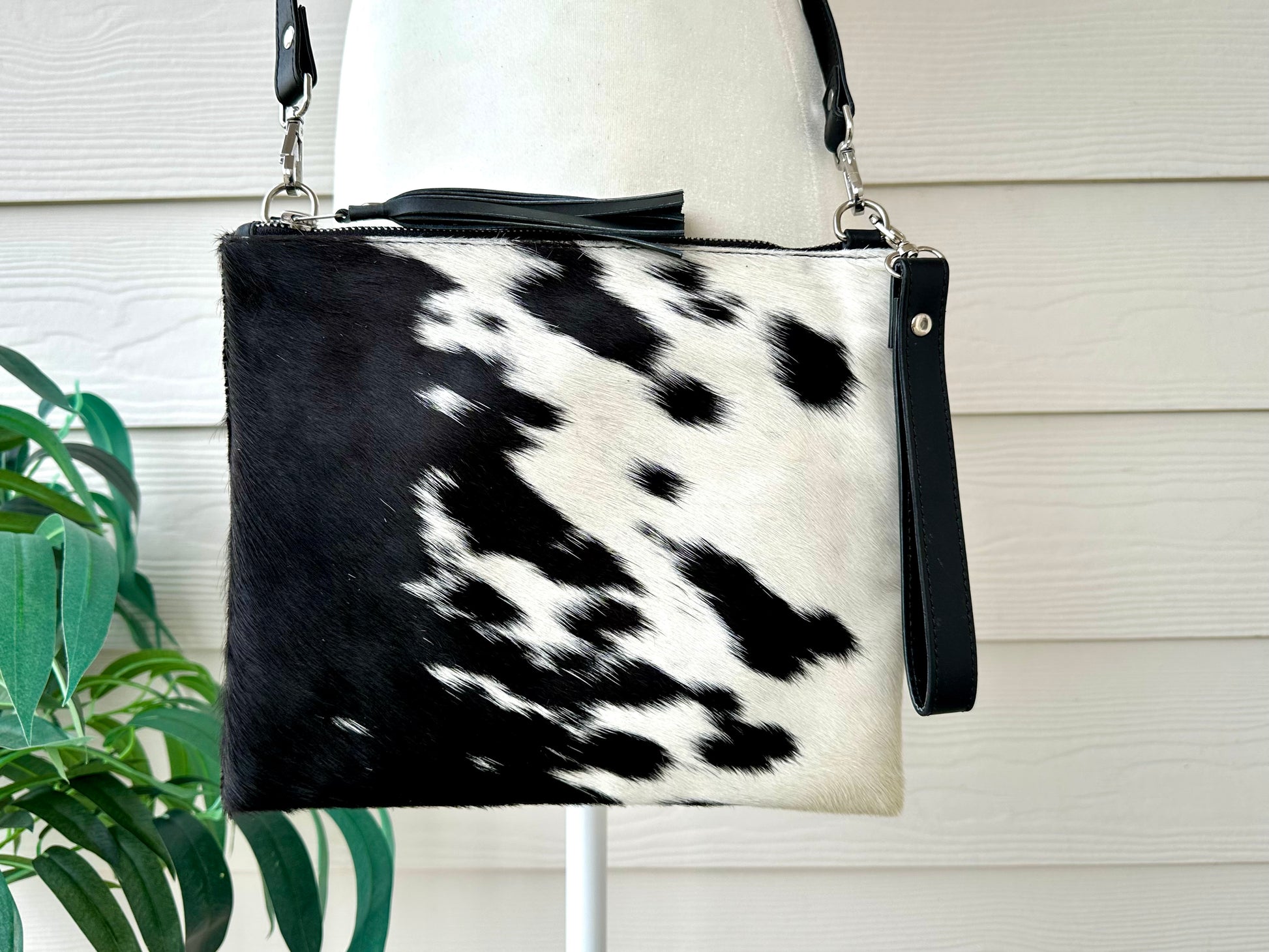 Handcrafted genuine cowhide crossbody purse with hair-on-hide front, leather tassel, adjustable strap, and western leather design for everyday wear, travel, rodeos, and concerts.