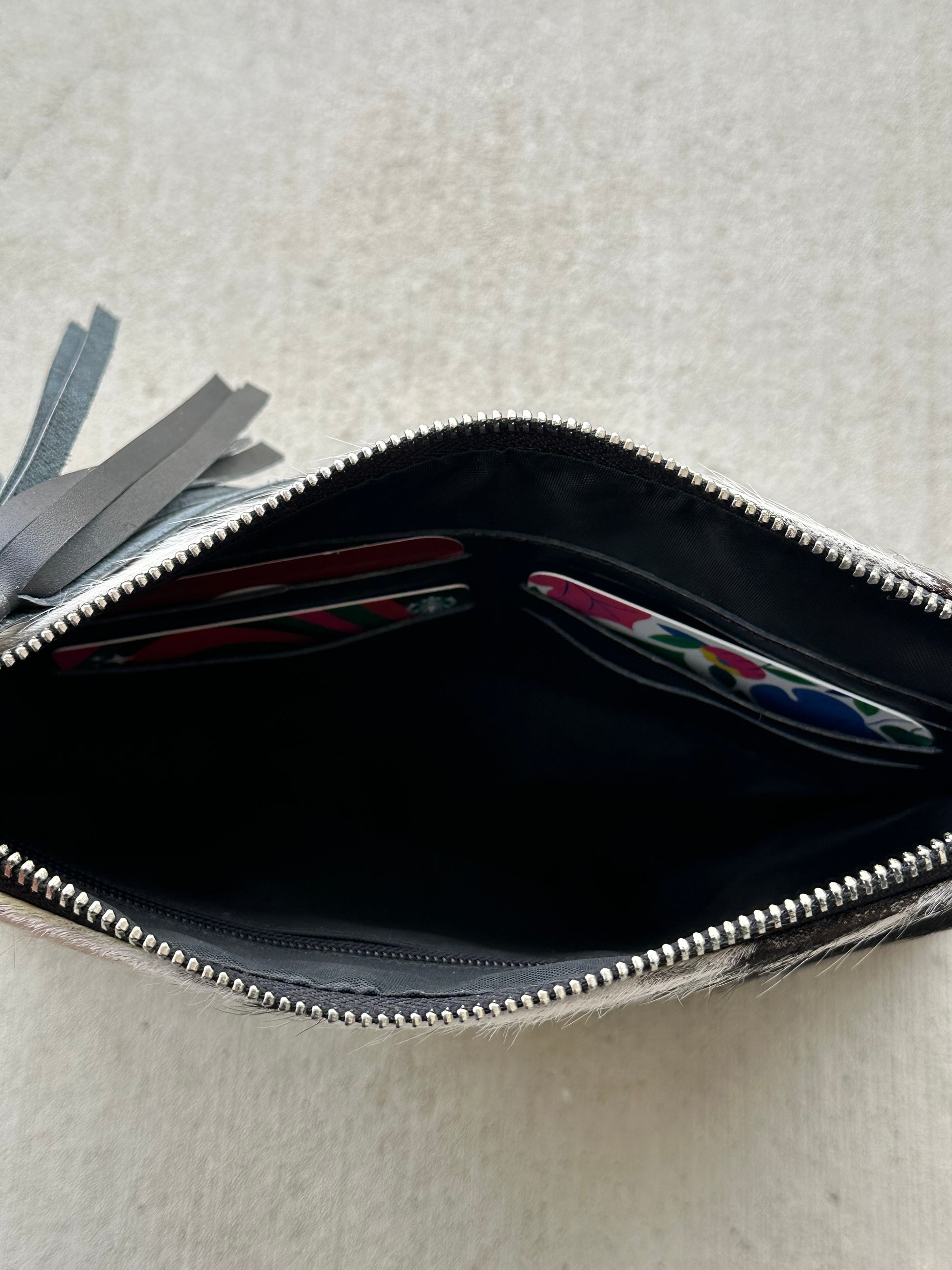 Handcrafted genuine cowhide crossbody purse with hair-on-hide front, leather tassel, adjustable strap, and western leather design for everyday wear, travel, rodeos, and concerts.
