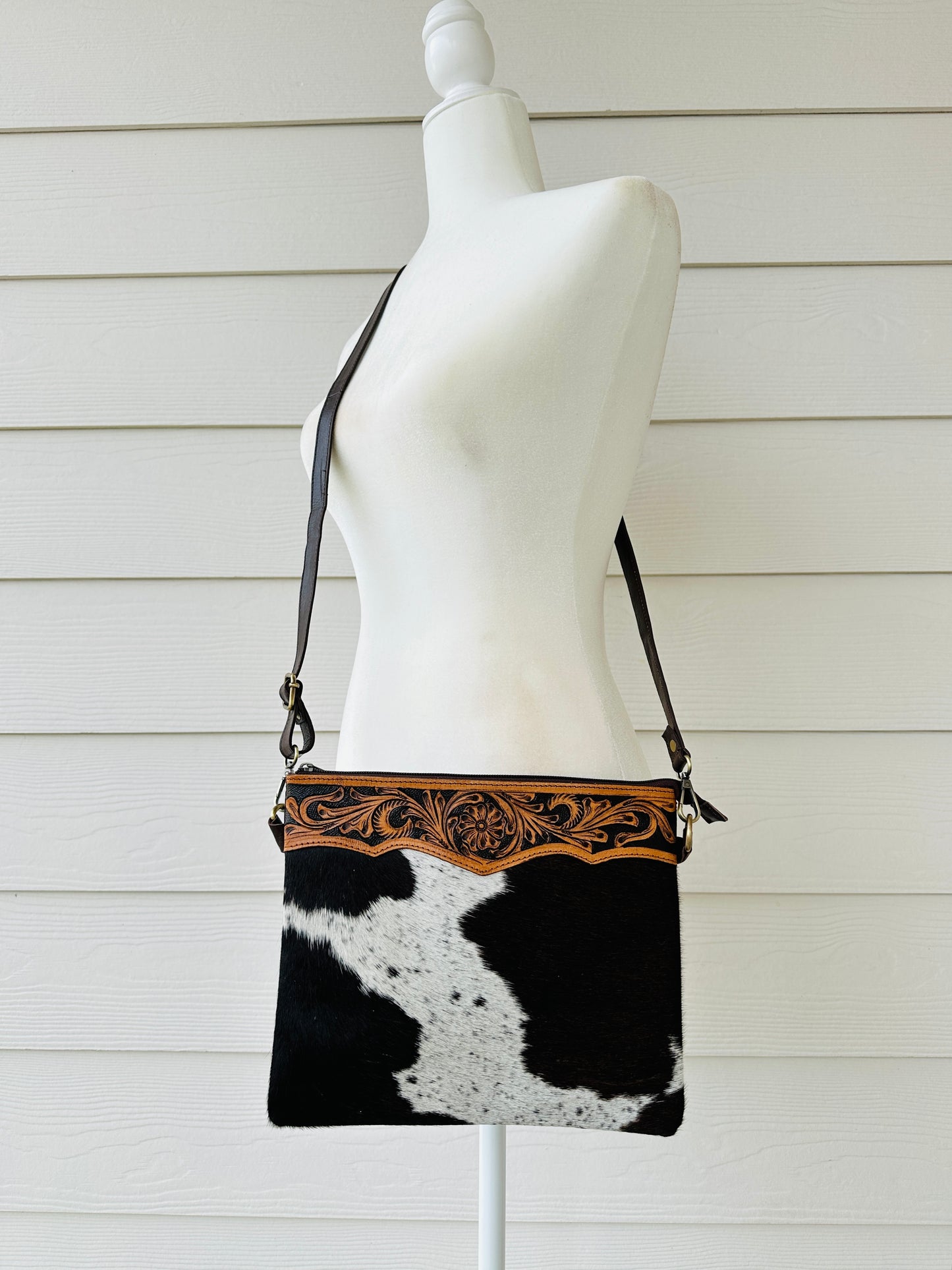 Handcrafted genuine cowhide crossbody purse with floral tooled leather zipper accent, adjustable leather strap, and western hair-on-hide design for everyday wear and rodeos.