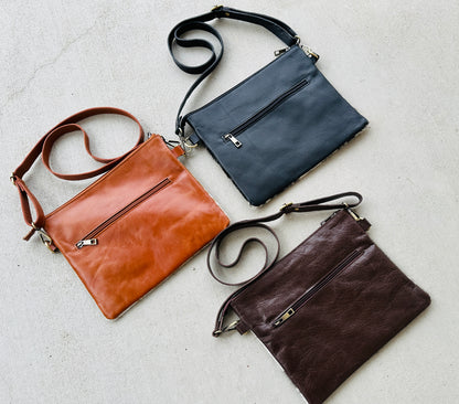 Handcrafted genuine cowhide crossbody purse with floral tooled leather zipper accent, adjustable leather strap, and western hair-on-hide design for everyday wear and rodeos.