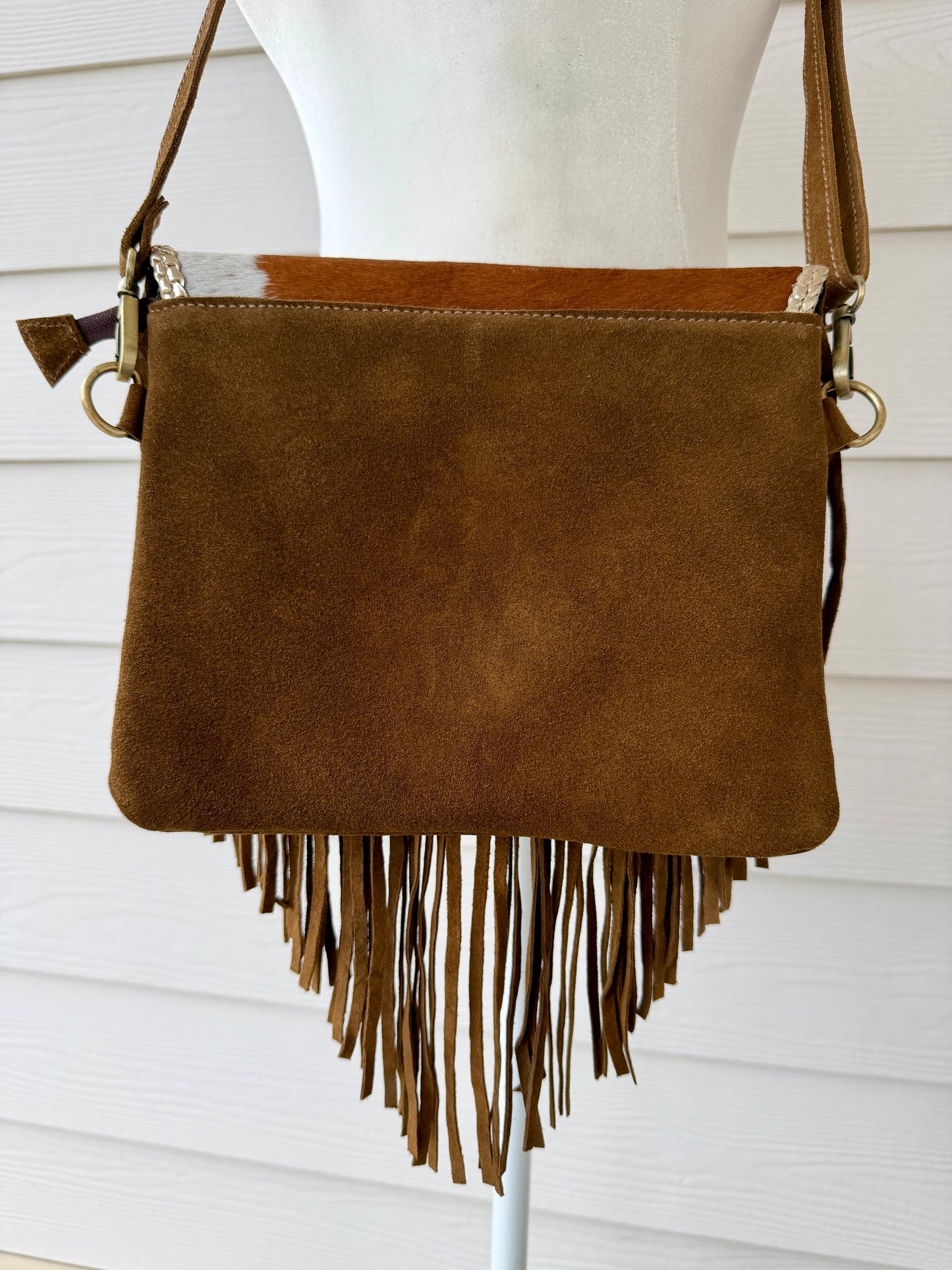 Handcrafted western cowhide crossbody bag with turquoise stone concho, whipstitched envelope flap, long leather fringe, and adjustable strap for rodeos, concerts, and everyday wear.