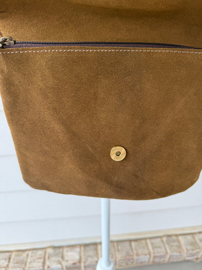 Handcrafted western cowhide crossbody bag with turquoise stone concho, whipstitched envelope flap, long leather fringe, and adjustable strap for rodeos, concerts, and everyday wear.