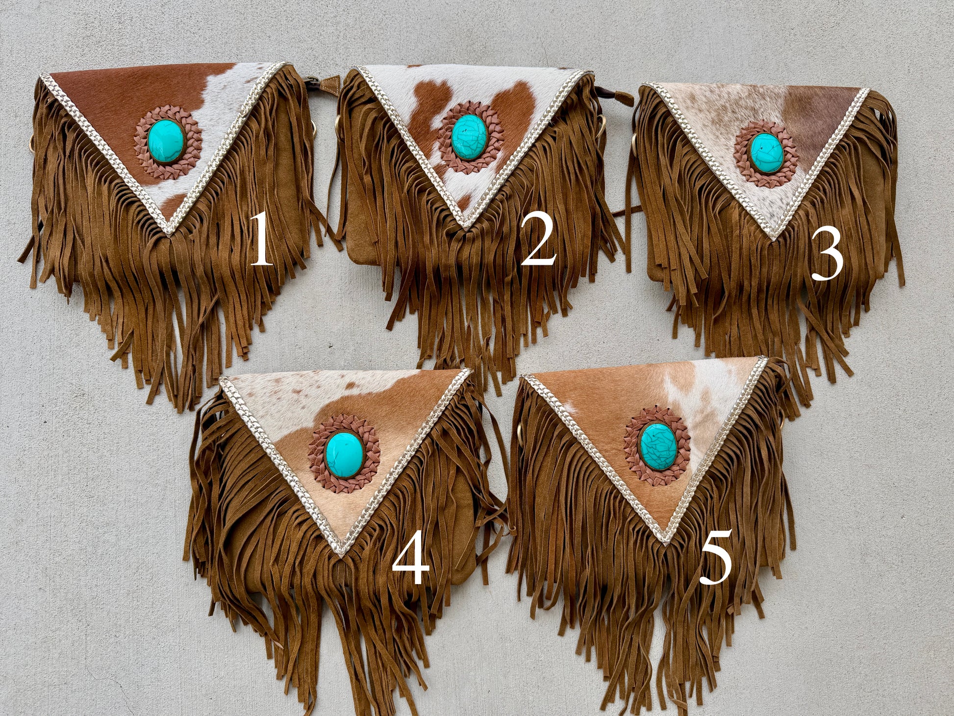 Handcrafted western cowhide crossbody bag with turquoise stone concho, whipstitched envelope flap, long leather fringe, and adjustable strap for rodeos, concerts, and everyday wear.