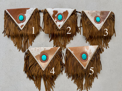 Handcrafted western cowhide crossbody bag with turquoise stone concho, whipstitched envelope flap, long leather fringe, and adjustable strap for rodeos, concerts, and everyday wear.