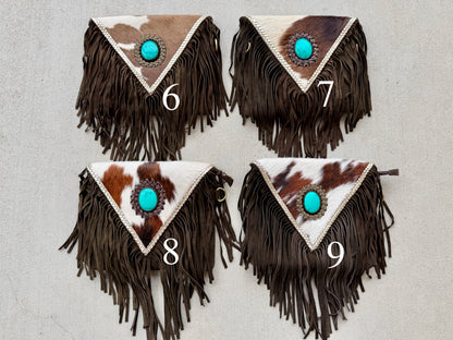 Handcrafted western cowhide crossbody bag with turquoise stone concho, whipstitched envelope flap, long leather fringe, and adjustable strap for rodeos, concerts, and everyday wear.