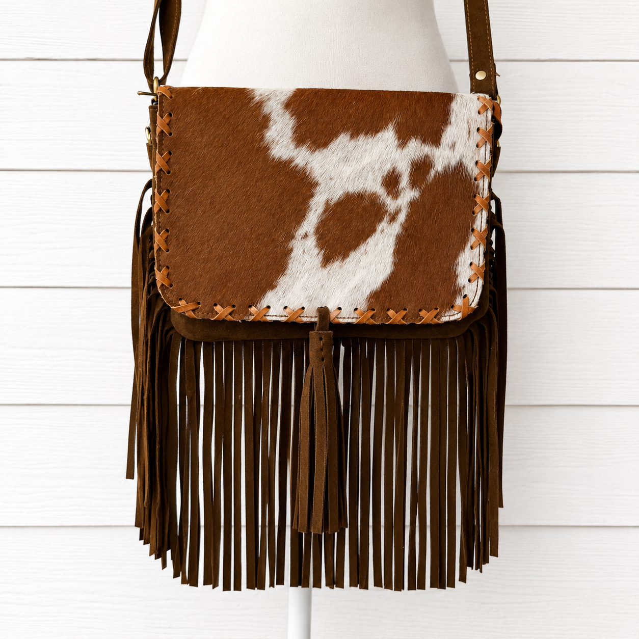 Handcrafted genuine cowhide fringe crossbody purse with whipstitched flap, leather tassel, adjustable strap, and western hair-on-hide design for rodeos, concerts, and everyday wear.