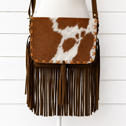 Handcrafted genuine cowhide fringe crossbody purse with whipstitched flap, leather tassel, adjustable strap, and western hair-on-hide design for rodeos, concerts, and everyday wear.